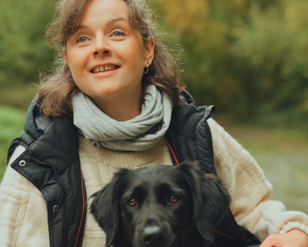 Porträt von Hundetrainerin Ellie Wilhelm mit ihrem schwarzen Hund Enni.